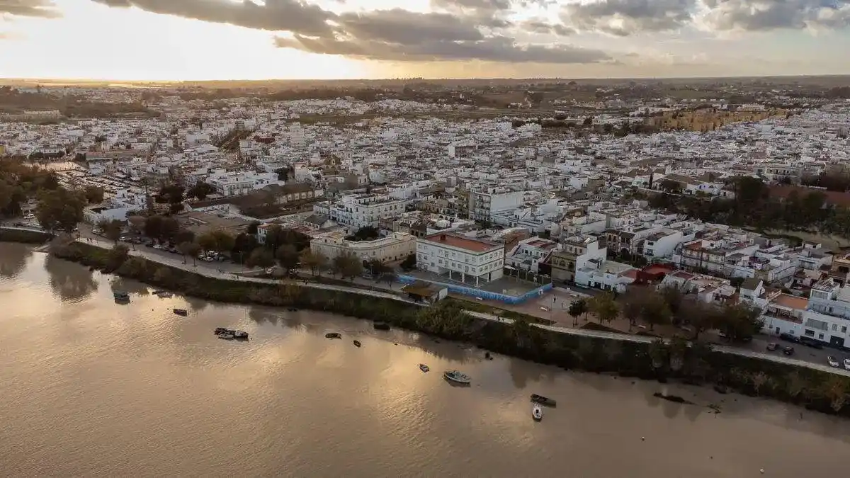 Equipo de mudanzas La Seda cargando muebles en una calle de Coria del Río junto al Guadalquivir con camión marcado